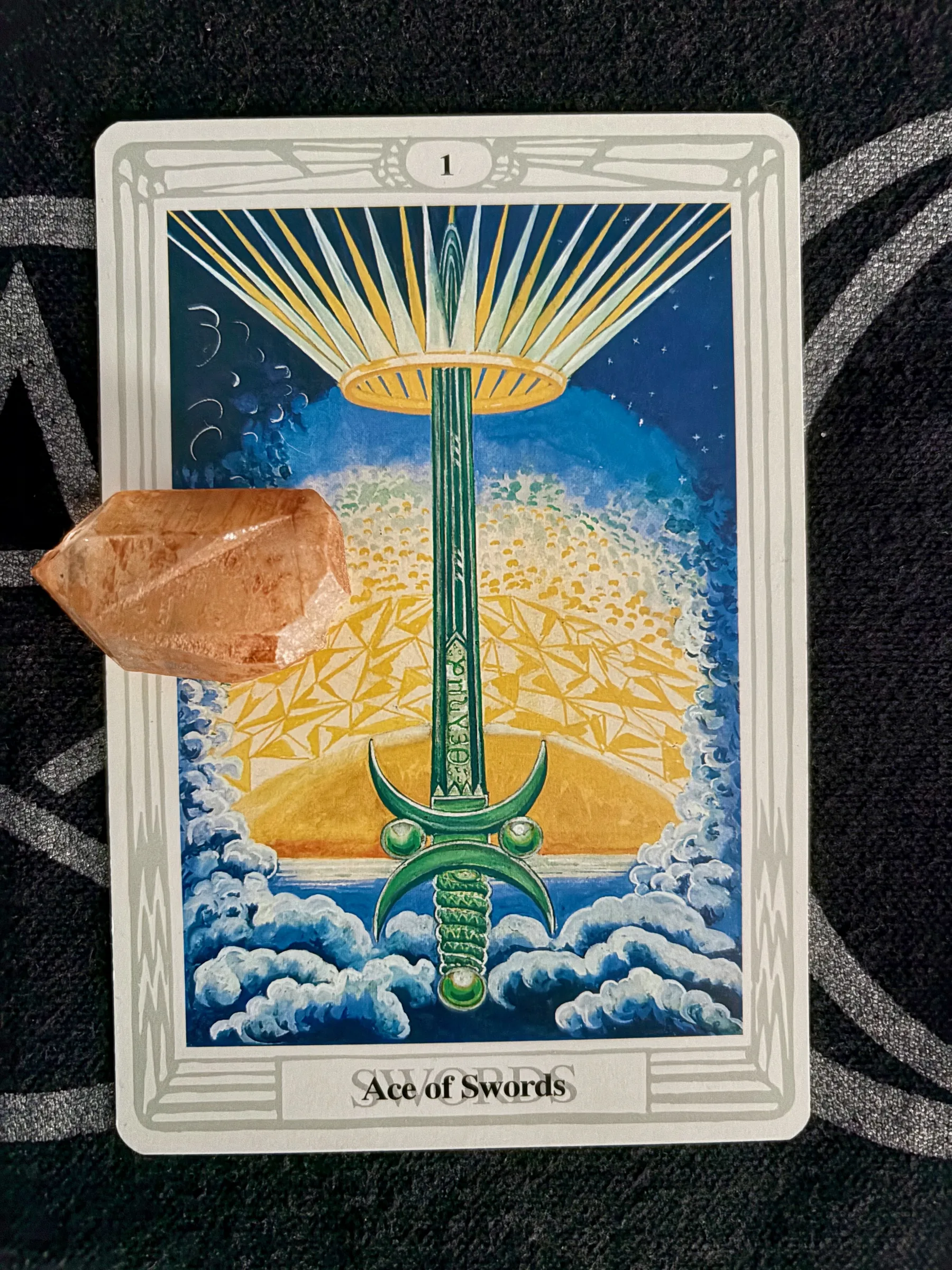 Tarot card Ace of Swords showing a green sword with a sunburst on a golden-yellow background.
