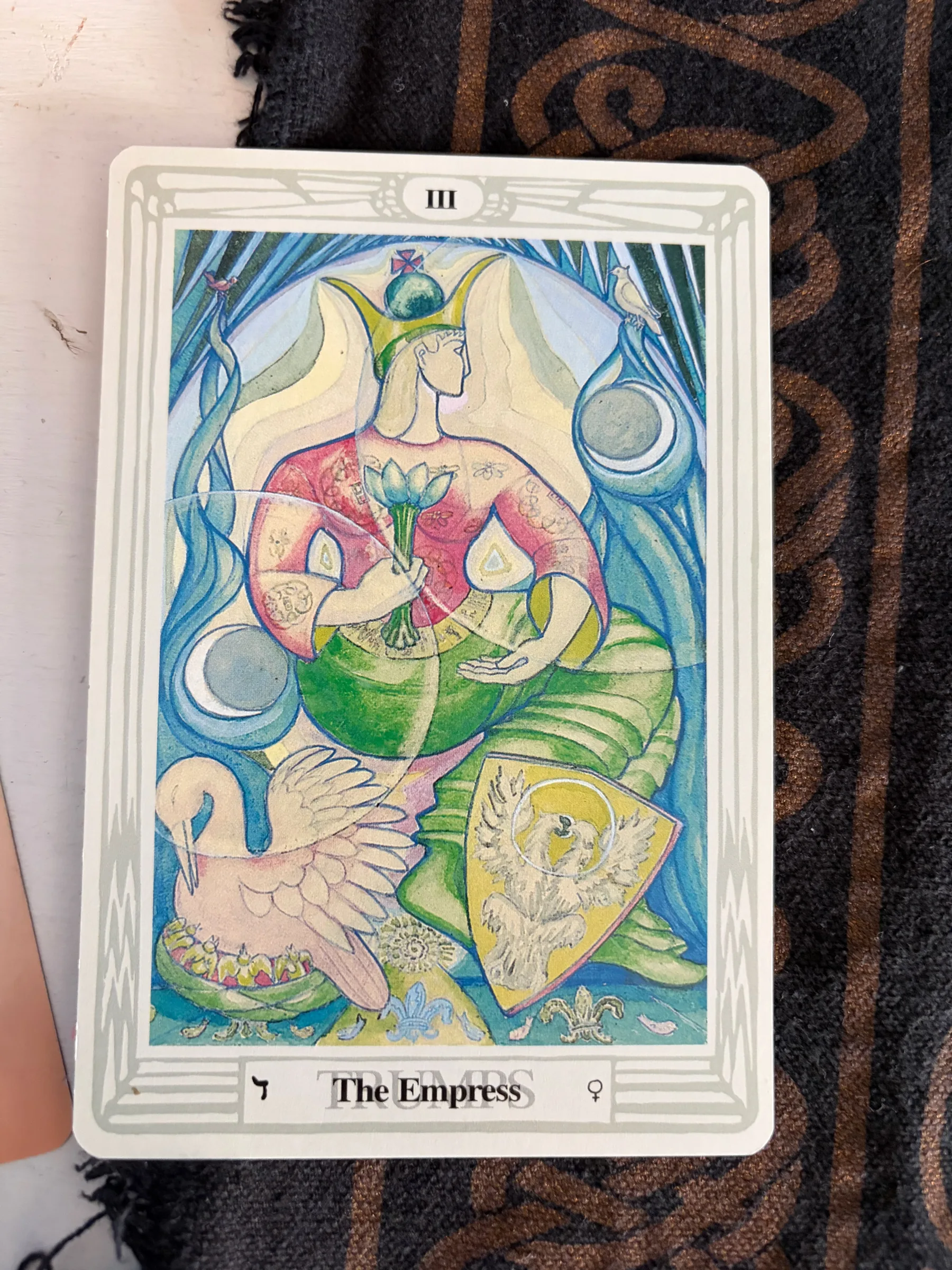 Illustrated Tarot card of The Empress featuring a woman holding flowers and symbolic elements.